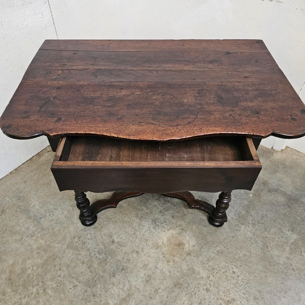 An 18th-century dark walnut side table featuring turned legs, a shaped lower apron, a moulded top, and a curved X-frame stretcher. View III