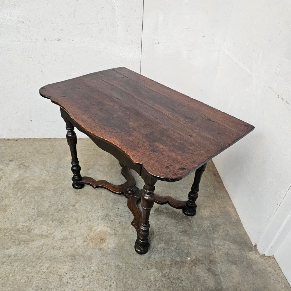 An 18th-century dark walnut side table featuring turned legs, a shaped lower apron, a moulded top, and a curved X-frame stretcher. View V