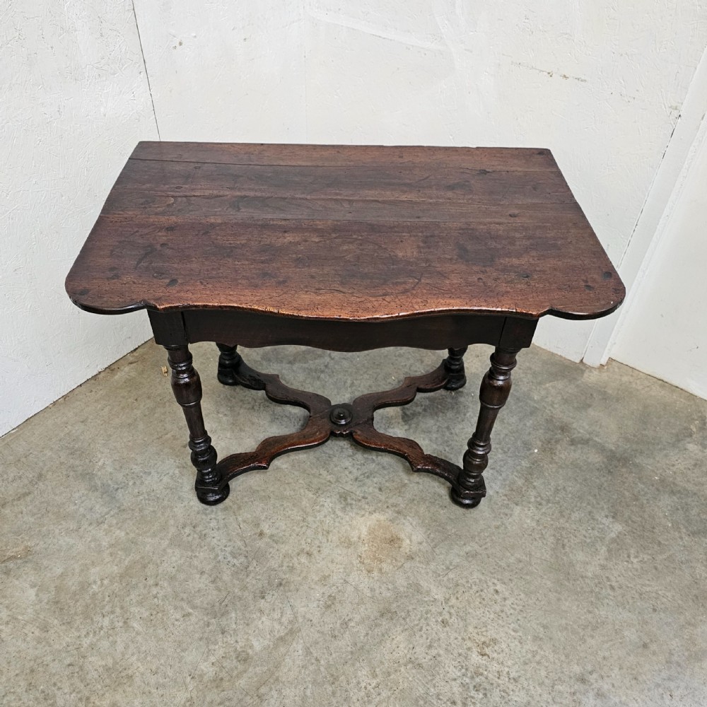 An 18th-century dark walnut side table featuring turned legs, a shaped lower apron, a moulded top, and a curved X-frame stretcher. View VI