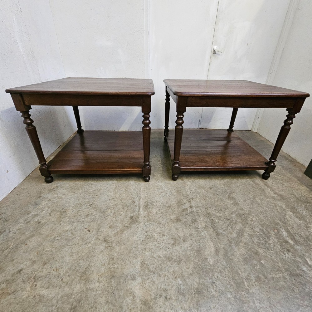 A matching pair of dark French oak square low display tables featuring turned legs and a solid lower tier shelf.