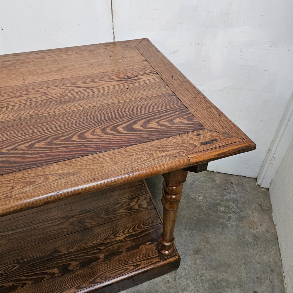 A 19th-century French pine drapers table featuring a long plank top, six turned legs, and a full-length lower pot board shelf. View V
