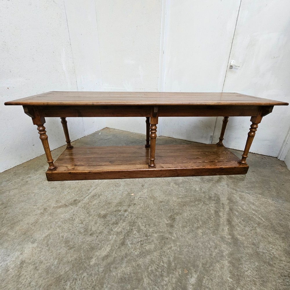 A 19th-century French pine drapers table featuring a long plank top, six turned legs, and a full-length lower pot board shelf. View III