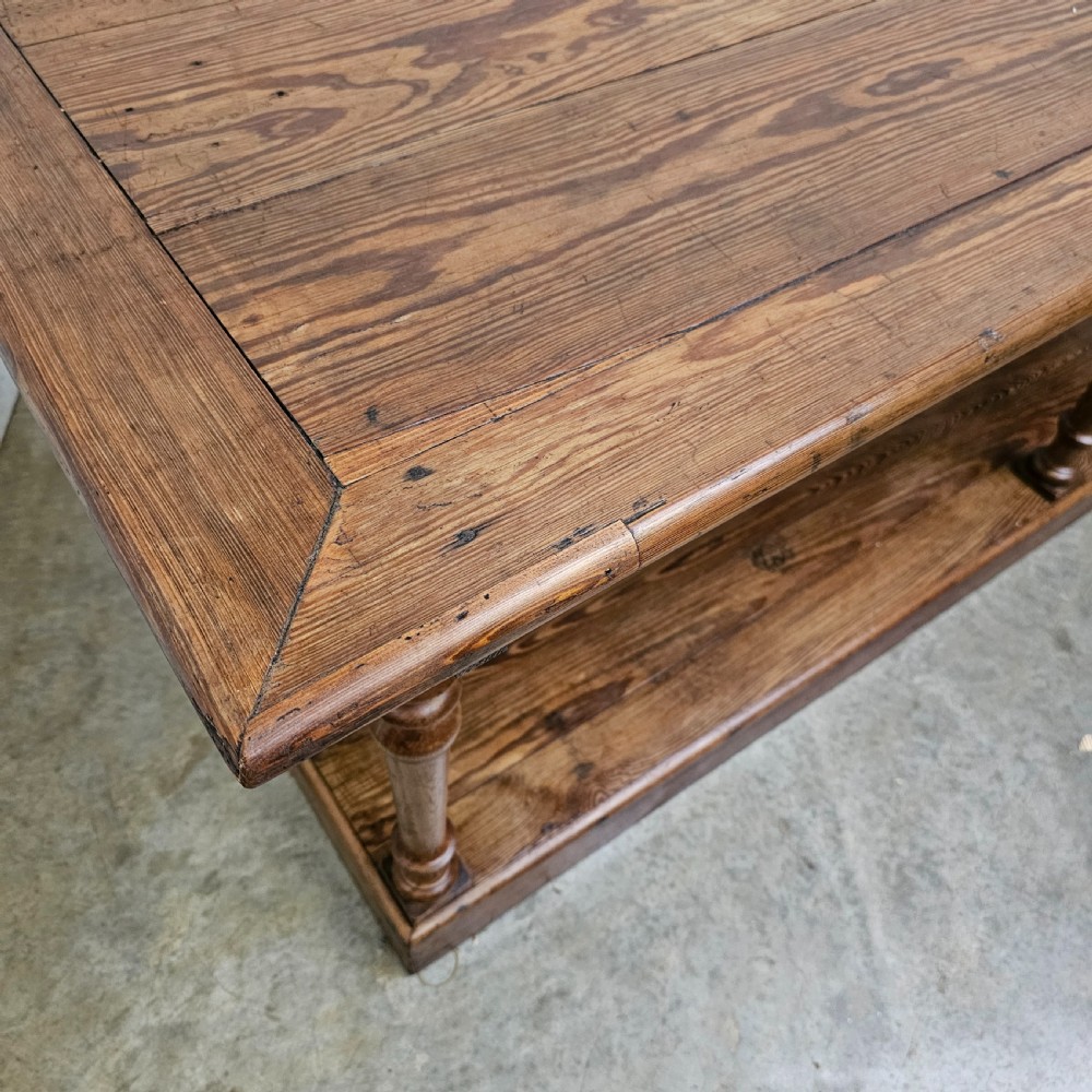 A 19th-century French pine drapers table featuring a long plank top, six turned legs, and a full-length lower pot board shelf. View VI