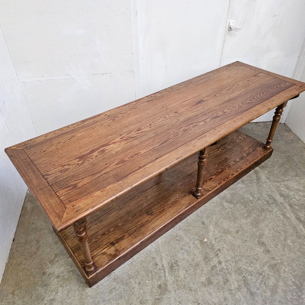 A 19th-century French pine drapers table featuring a long plank top, six turned legs, and a full-length lower pot board shelf. View VII