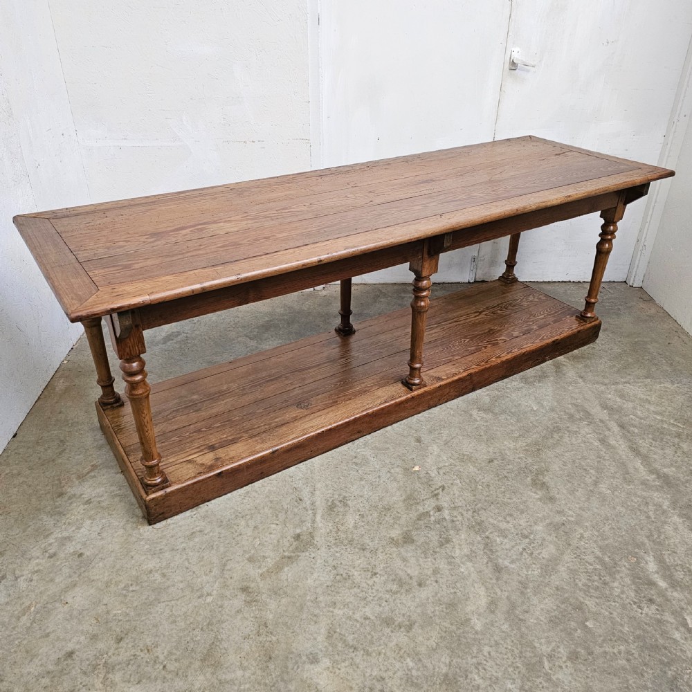 A 19th-century French pine drapers table featuring a long plank top, six turned legs, and a full-length lower pot board shelf. View VIII