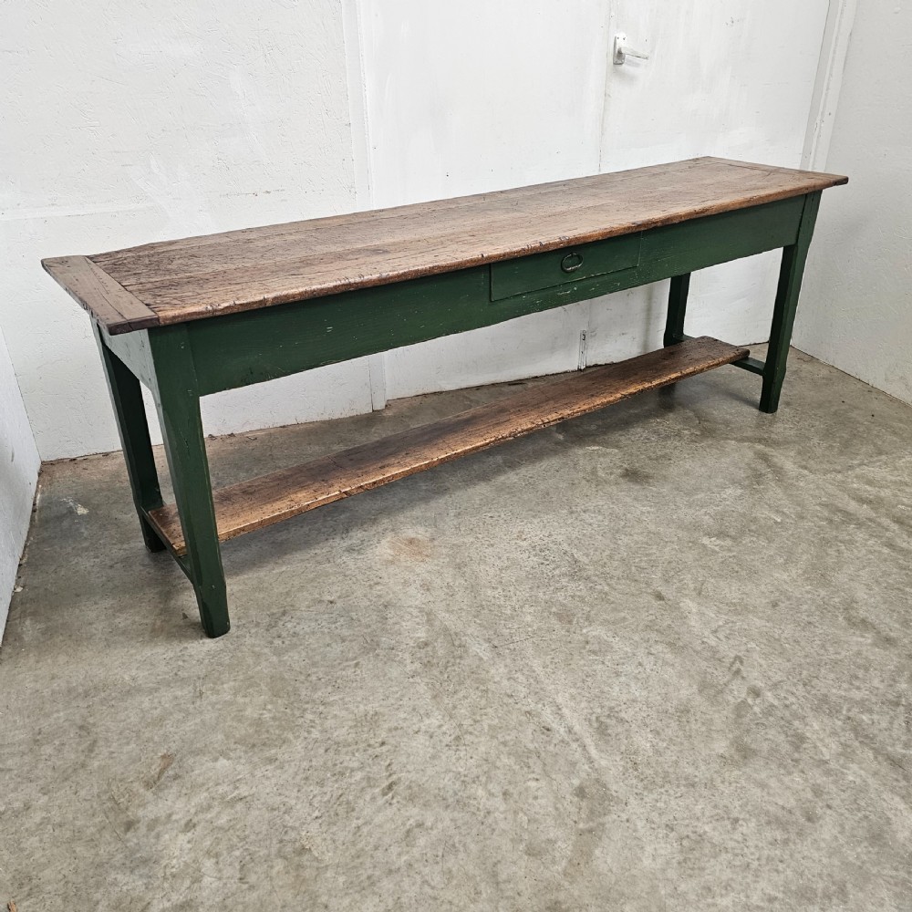 A long rustic French serving table featuring a dark green painted wooden frame, a single drawer with an iron pull, a natural wood top, and a lower pot shelf. View IV
