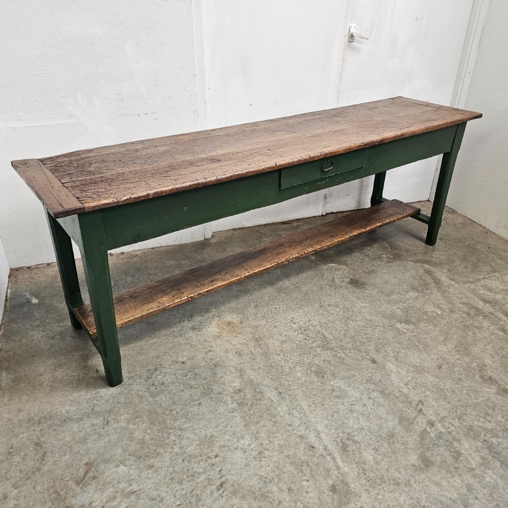 A long rustic French serving table featuring a dark green painted wooden frame, a single drawer with an iron pull, a natural wood top, and a lower pot shelf. View V