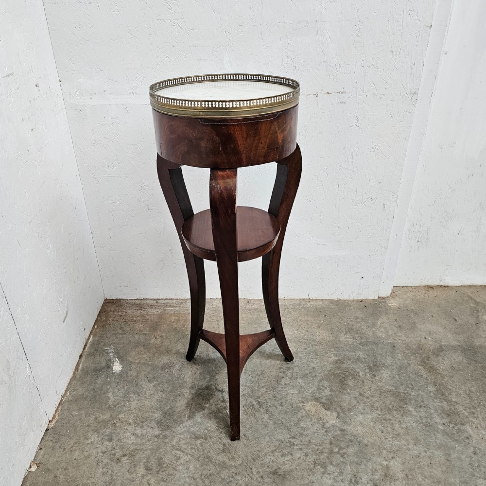 A tall French mahogany tripod stand featuring an inset circular white marble top with a pierced brass gallery and a lower circular shelf.