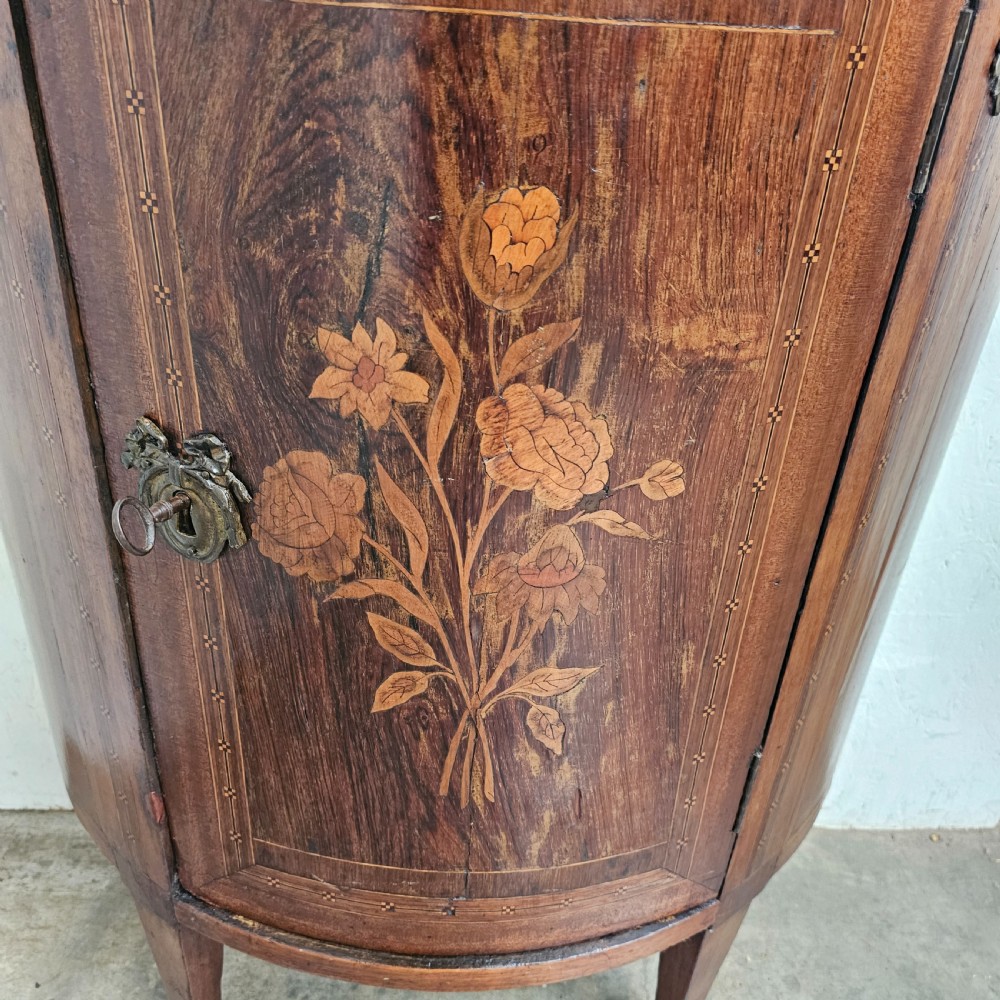A French Louis XVI style demi-lune console cabinet featuring dark wood finish, floral marquetry inlay on the single door, dark marble top, and tapered legs. View II
