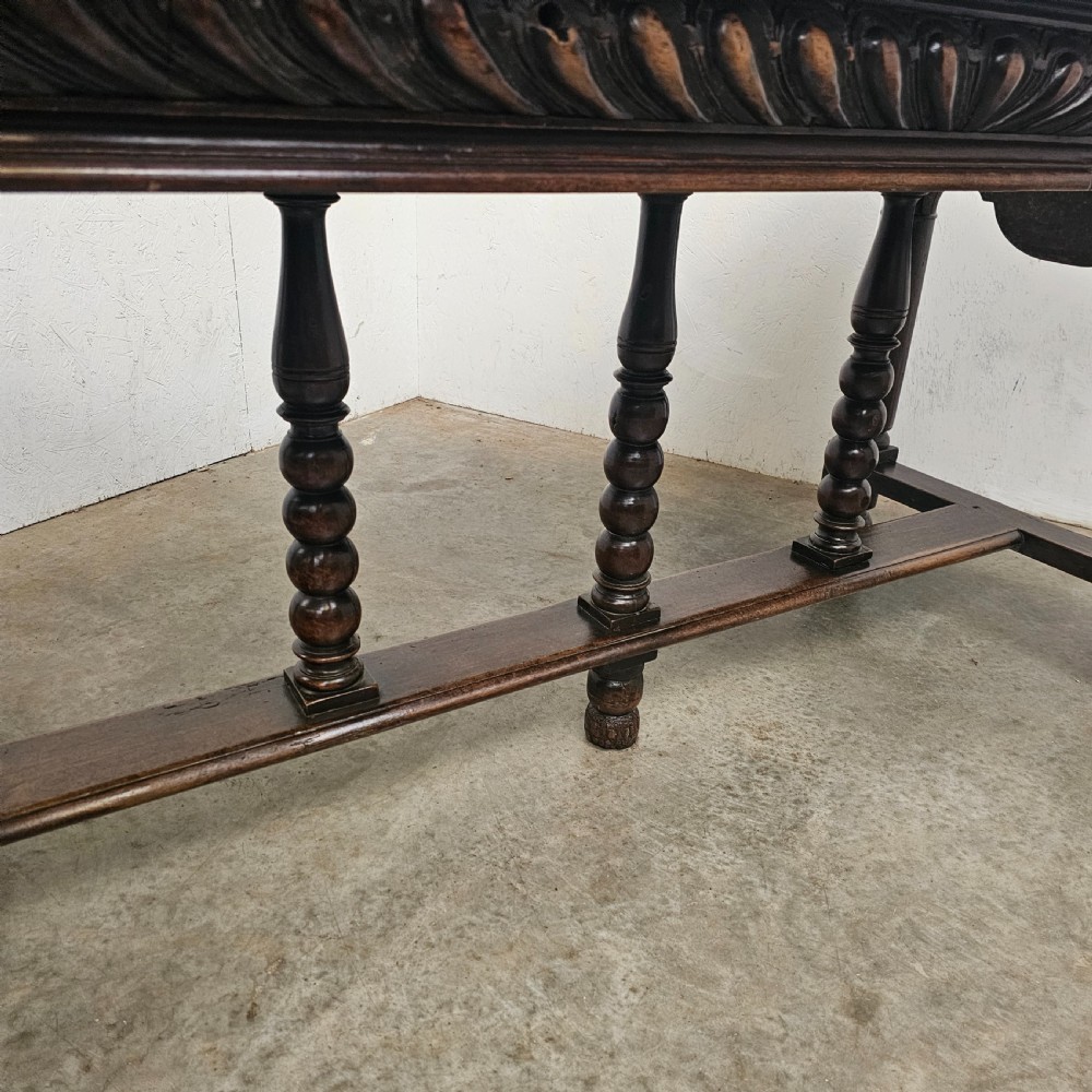 A rectangular dark walnut centre table featuring a deeply carved egg-and-dart frieze, turned column legs, and a central stretcher with spindle supports. View II