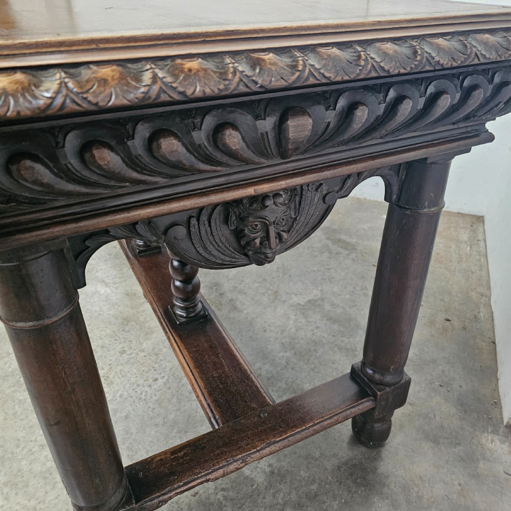 A rectangular dark walnut centre table featuring a deeply carved egg-and-dart frieze, turned column legs, and a central stretcher with spindle supports. View IV