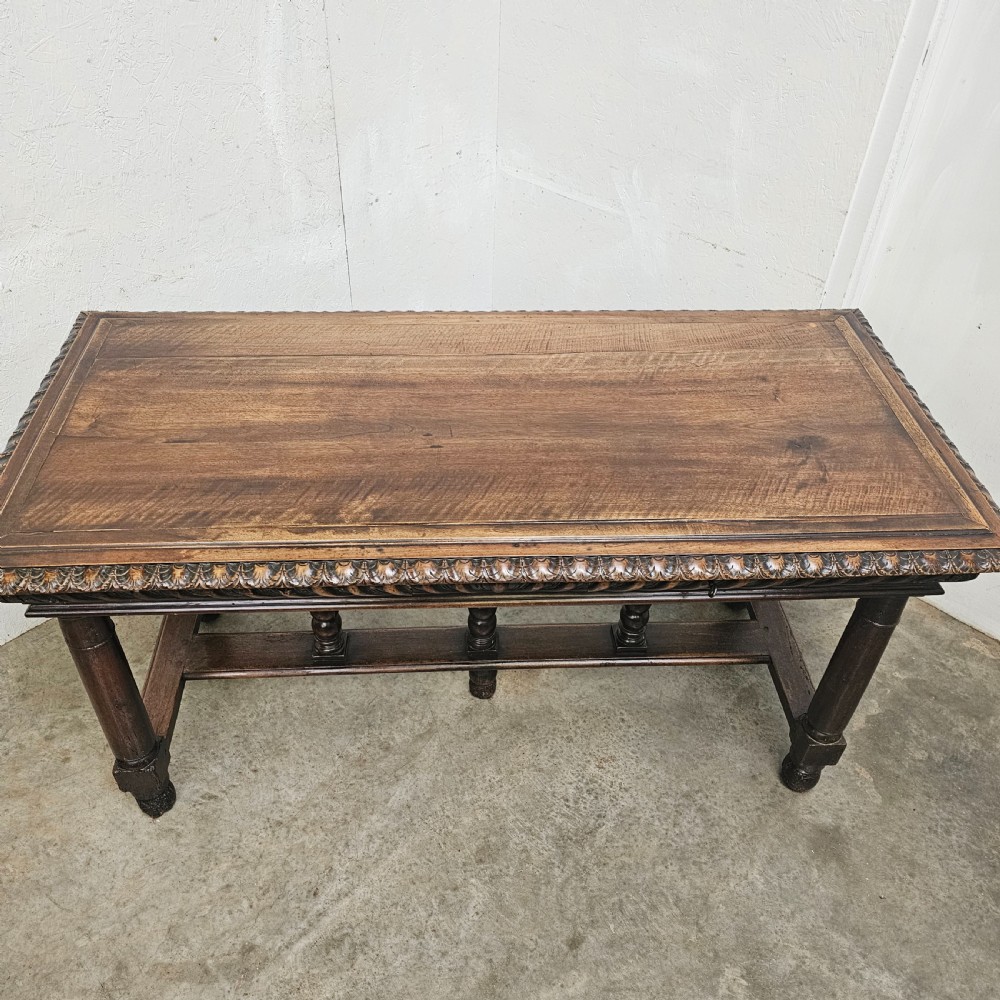 A rectangular dark walnut centre table featuring a deeply carved egg-and-dart frieze, turned column legs, and a central stretcher with spindle supports. View V