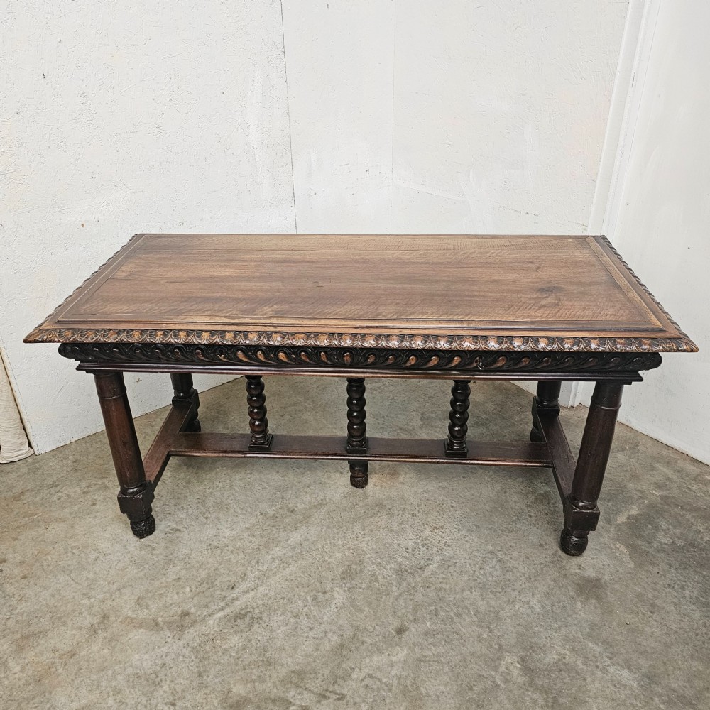 A rectangular dark walnut centre table featuring a deeply carved egg-and-dart frieze, turned column legs, and a central stretcher with spindle supports. View VIII