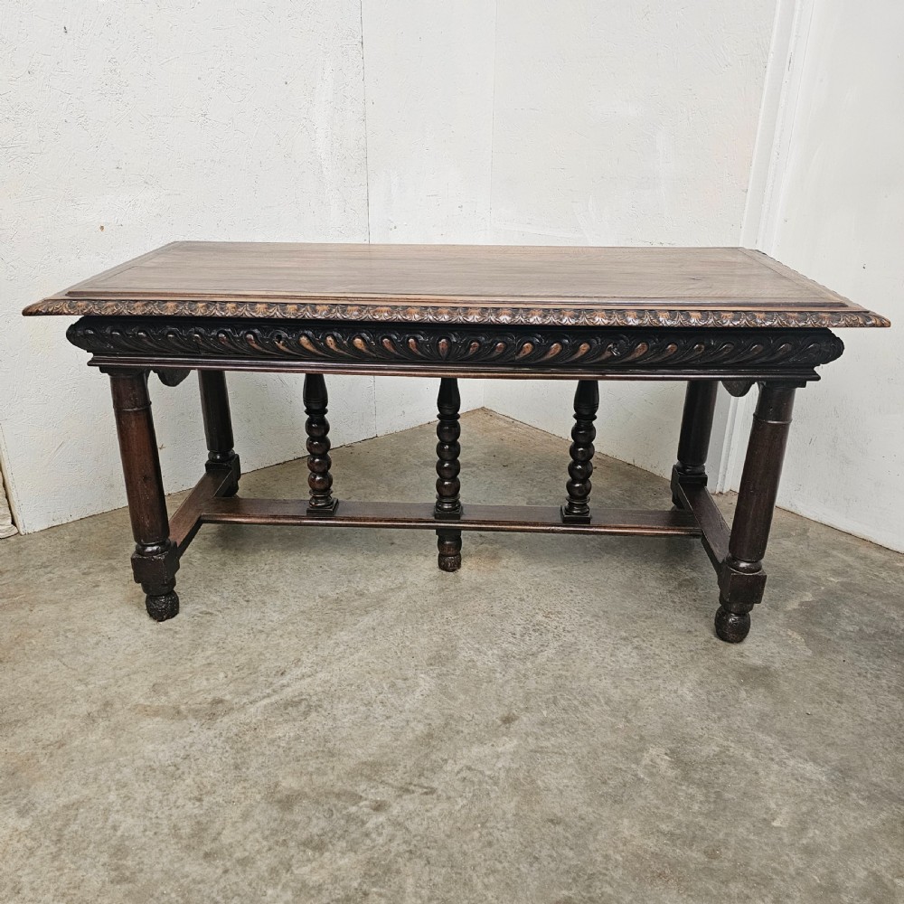A rectangular dark walnut centre table featuring a deeply carved egg-and-dart frieze, turned column legs, and a central stretcher with spindle supports.
