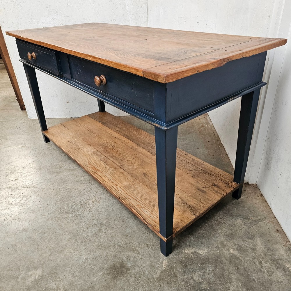 A French two-tier wooden work table featuring a dark blue painted frame, two drawers with round wooden handles, and natural light wood top and lower shelf. View V