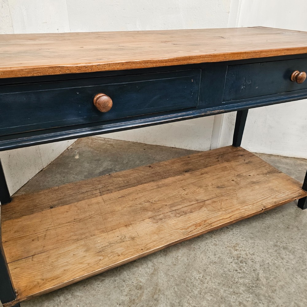 A French two-tier wooden work table featuring a dark blue painted frame, two drawers with round wooden handles, and natural light wood top and lower shelf. View VII