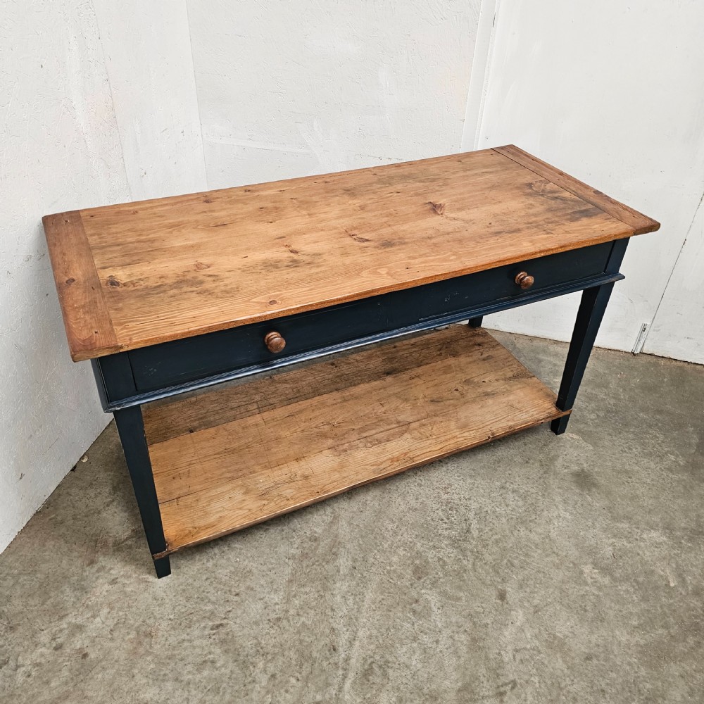A French two-tier wooden work table featuring a dark blue painted frame, two drawers with round wooden handles, and natural light wood top and lower shelf. View VIII