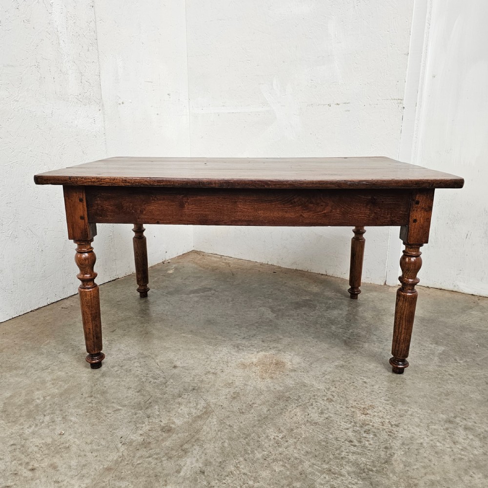 A low rectangular French oak table featuring a flat wooden top, deep apron, and four turned legs.