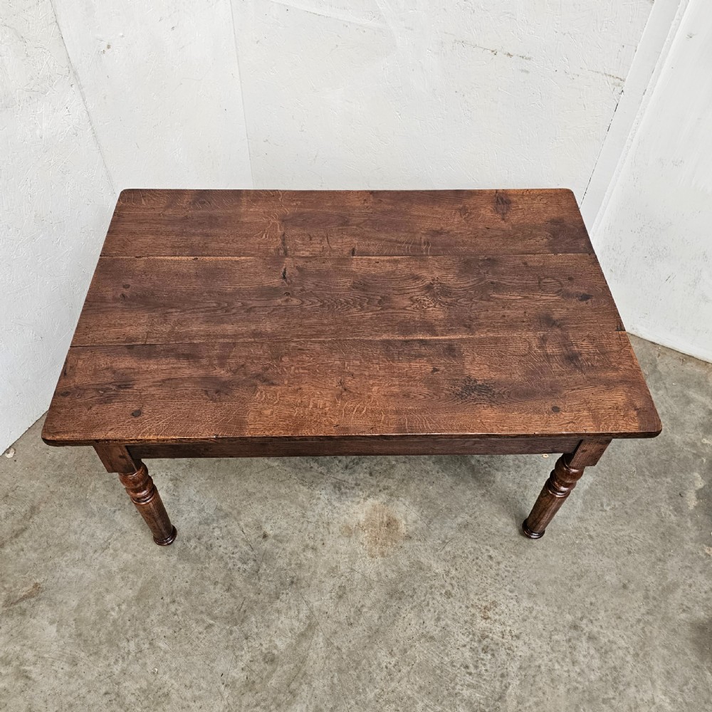 A low rectangular French oak table featuring a flat wooden top, deep apron, and four turned legs. View V