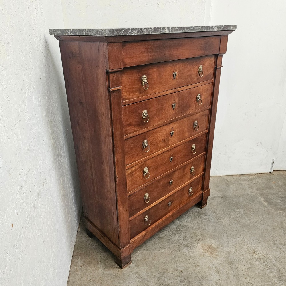 A nineteenth-century French cherry wood semainier featuring seven drawers with brass lion mask ring handles and a grey marble top. View IV