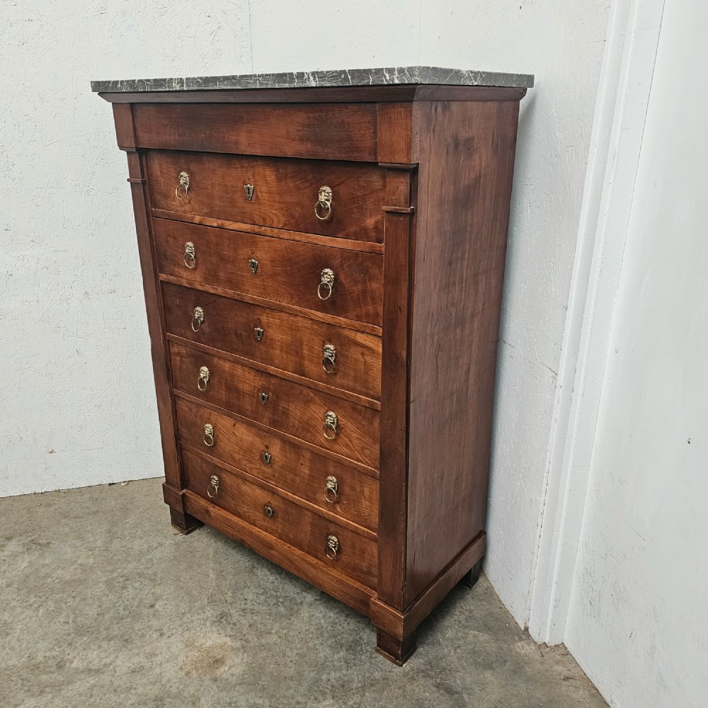 A nineteenth-century French cherry wood semainier featuring seven drawers with brass lion mask ring handles and a grey marble top. View V