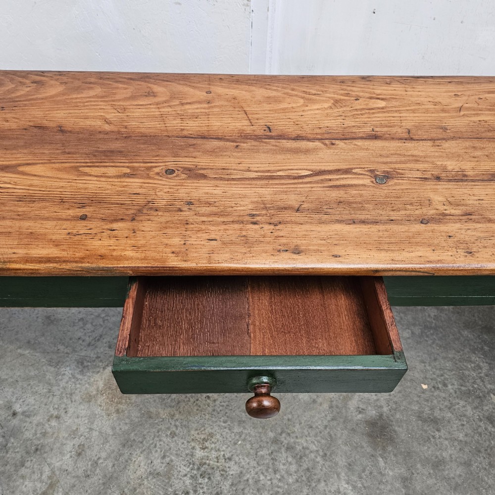 A long French painted pine console table featuring a natural wood plank top, a dark green painted base with tapered square legs, and three inline drawers with wooden knobs. View III