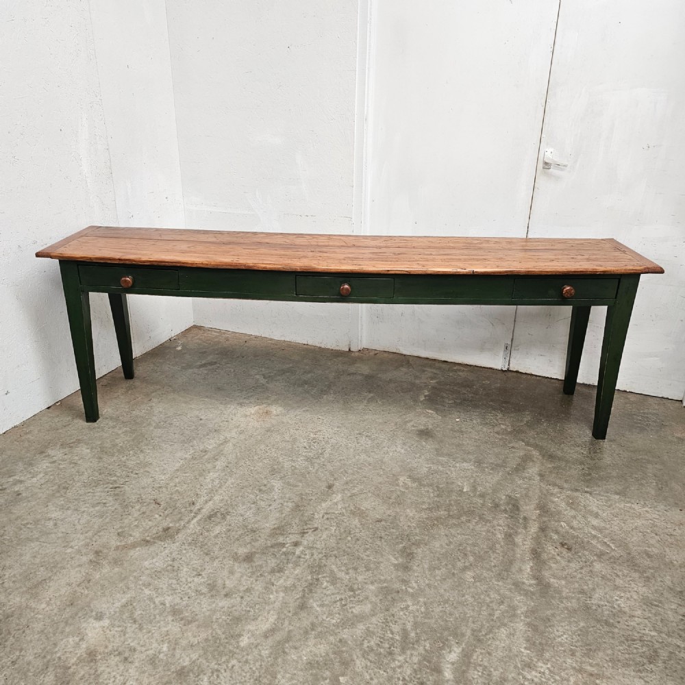 A long French painted pine console table featuring a natural wood plank top, a dark green painted base with tapered square legs, and three inline drawers with wooden knobs. View VI
