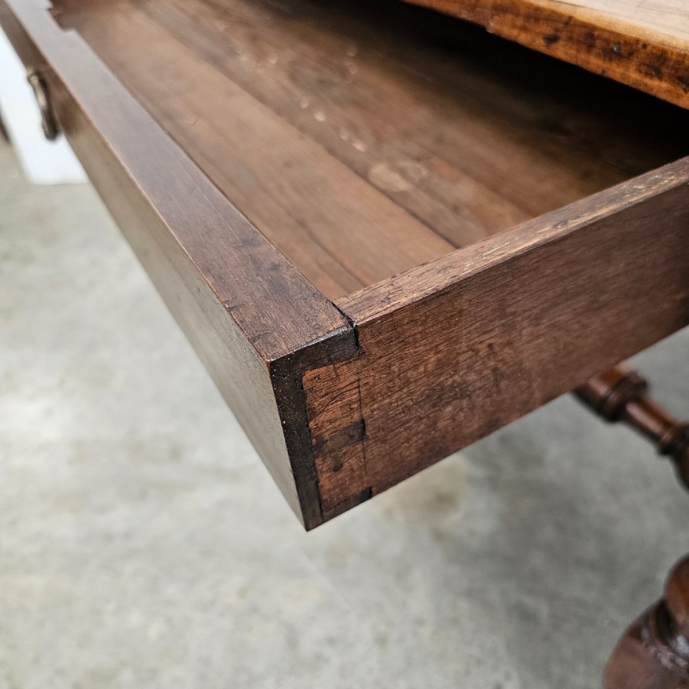 A warm brown cherry wood side table with turned legs, a low stretcher, and a single frieze drawer with a brass handle. View III