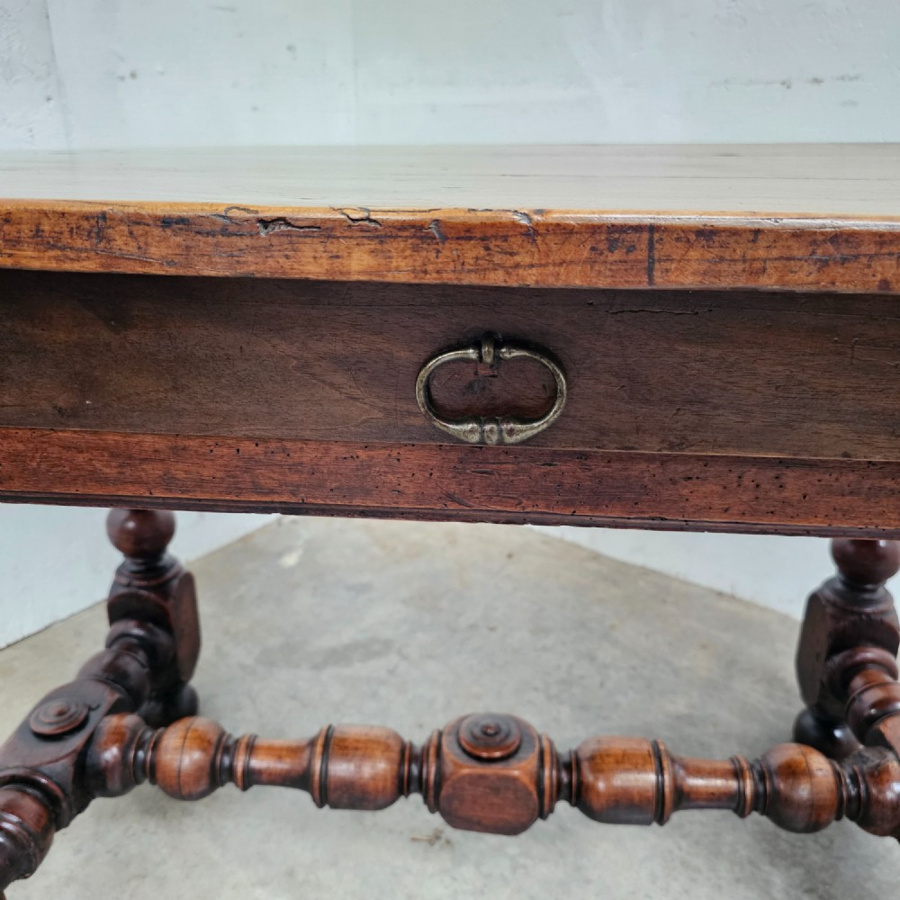 A warm brown cherry wood side table with turned legs, a low stretcher, and a single frieze drawer with a brass handle. View IV