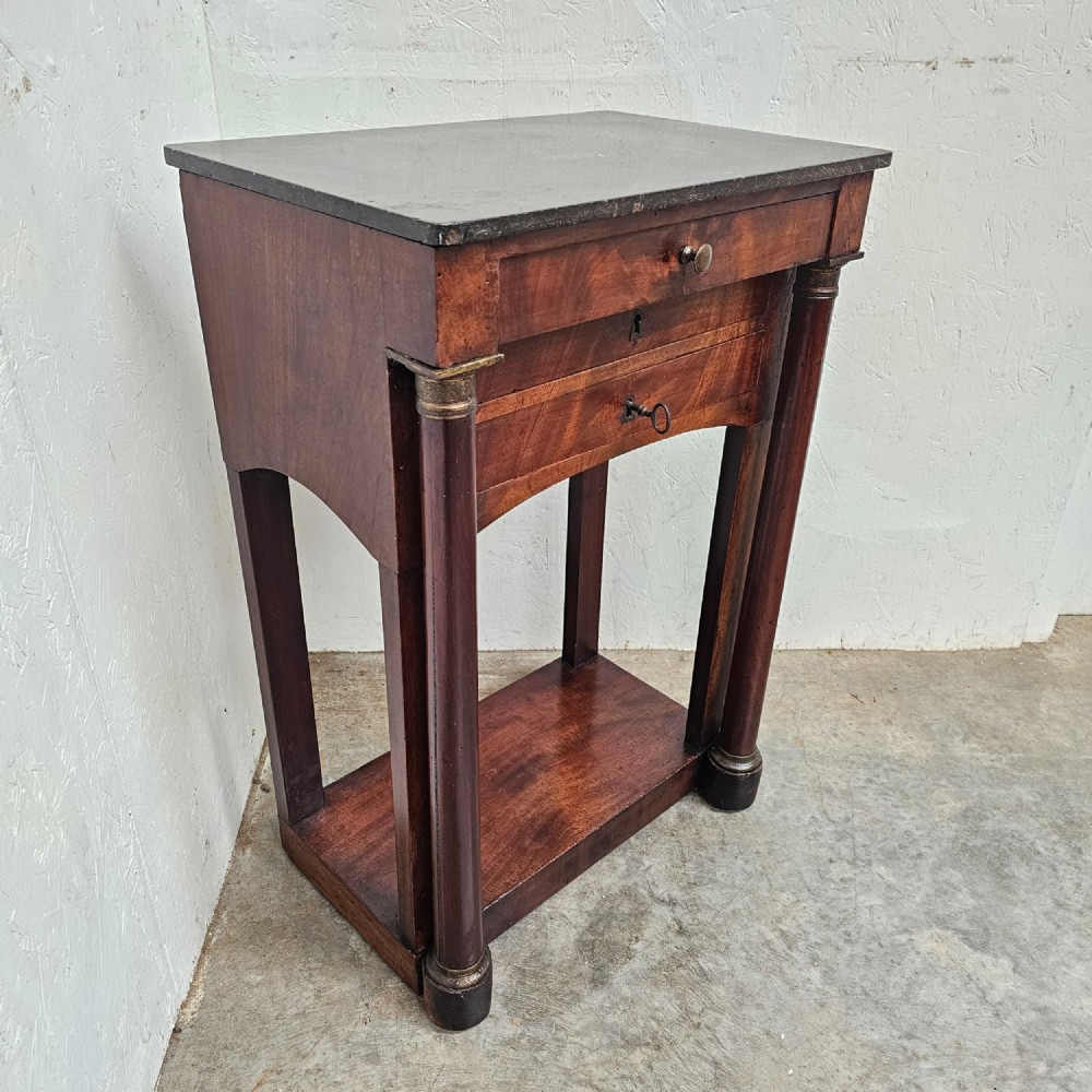 A French Empire style mahogany console table featuring a dark fossil marble top, twin side column supports, integrated drawers, and a lower tier undershelf. View II
