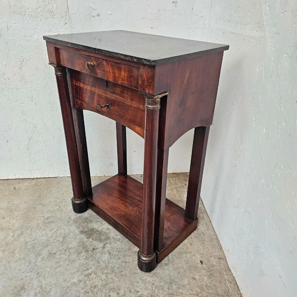A French Empire style mahogany console table featuring a dark fossil marble top, twin side column supports, integrated drawers, and a lower tier undershelf. View III