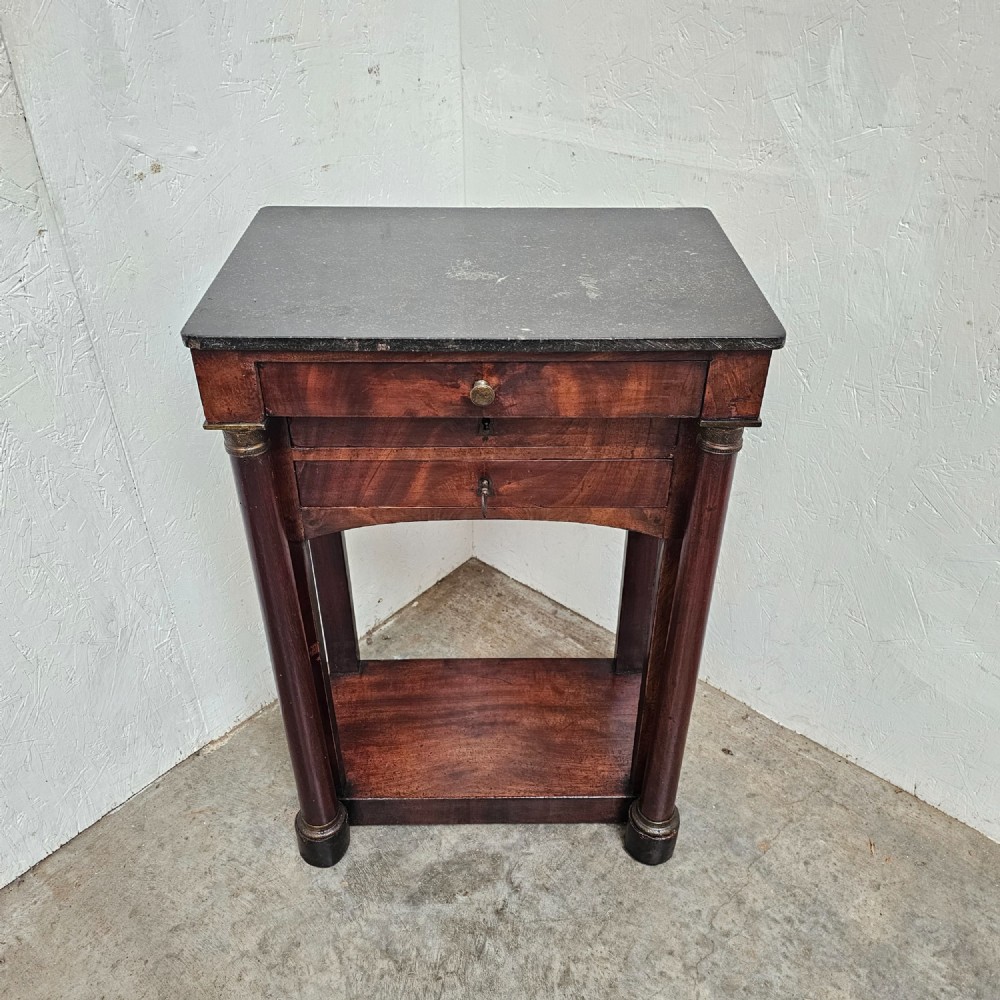 A French Empire style mahogany console table featuring a dark fossil marble top, twin side column supports, integrated drawers, and a lower tier undershelf. View IV