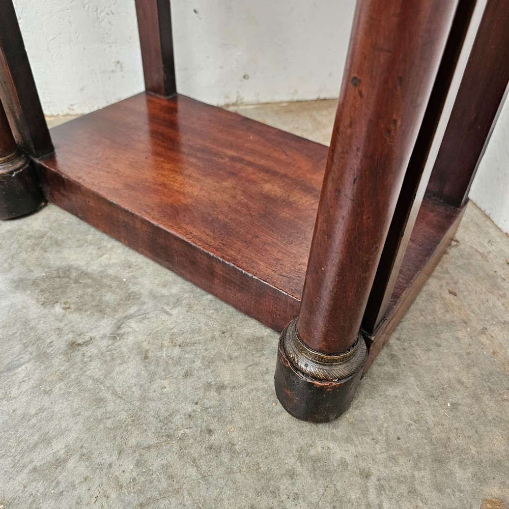 A French Empire style mahogany console table featuring a dark fossil marble top, twin side column supports, integrated drawers, and a lower tier undershelf. View VI