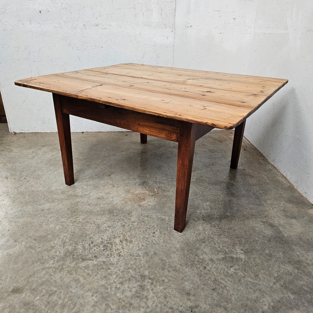 An antique table featuring an unvarnished scrubbed pine tabletop supported by a dark fruitwood base with square tapered legs. View II