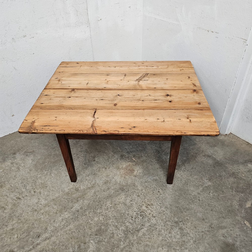 An antique table featuring an unvarnished scrubbed pine tabletop supported by a dark fruitwood base with square tapered legs. View III