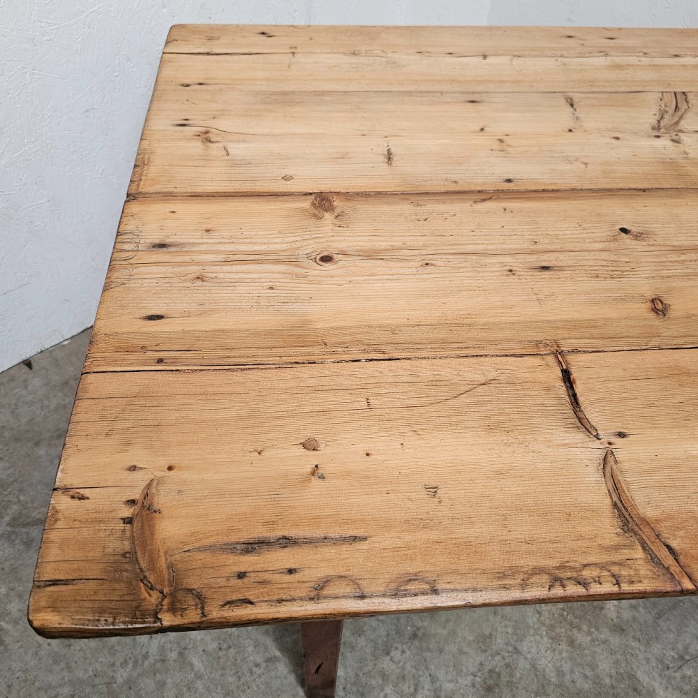 An antique table featuring an unvarnished scrubbed pine tabletop supported by a dark fruitwood base with square tapered legs. View V