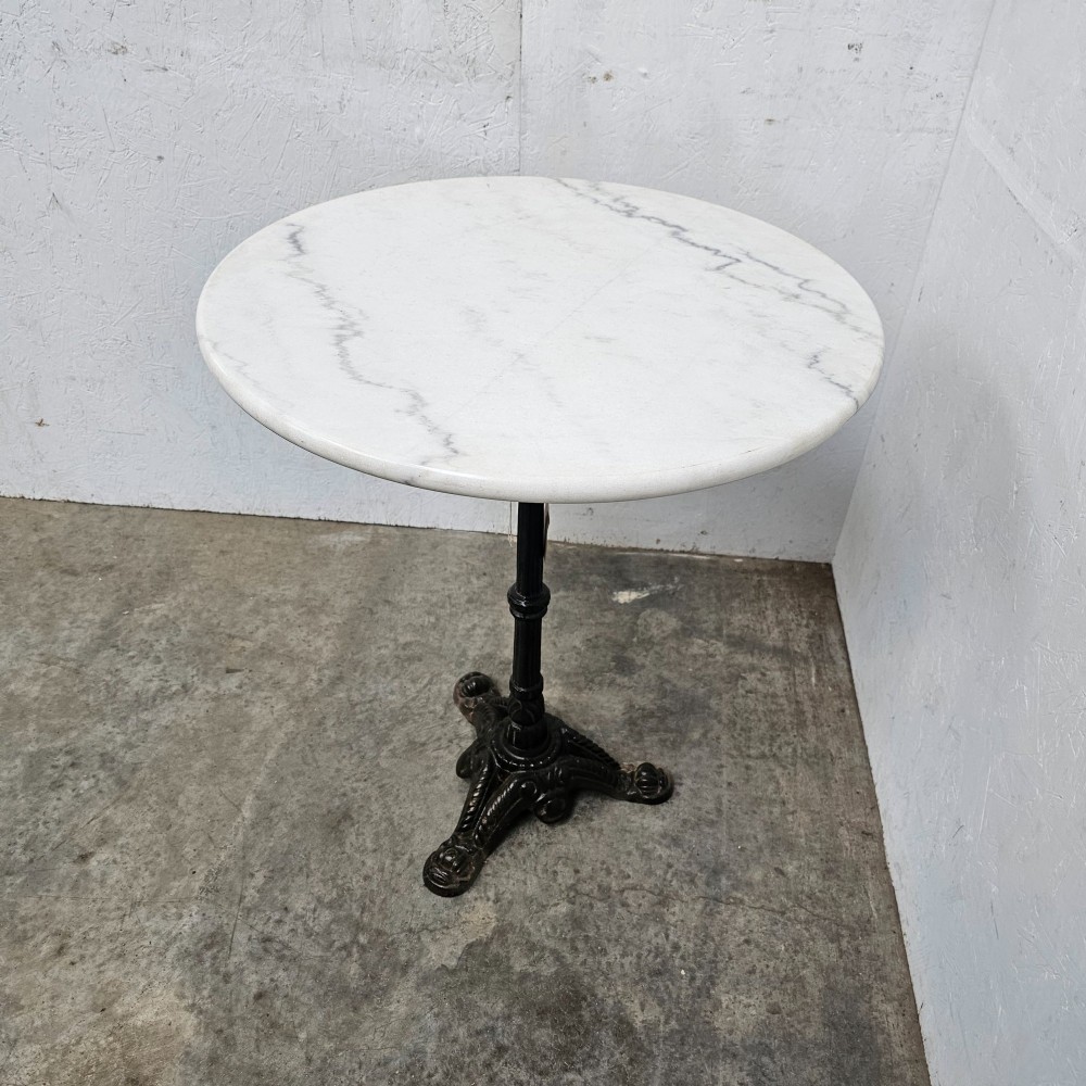A round white marble top bistro table supported by a black cast iron central column and ornate tripod base. View II