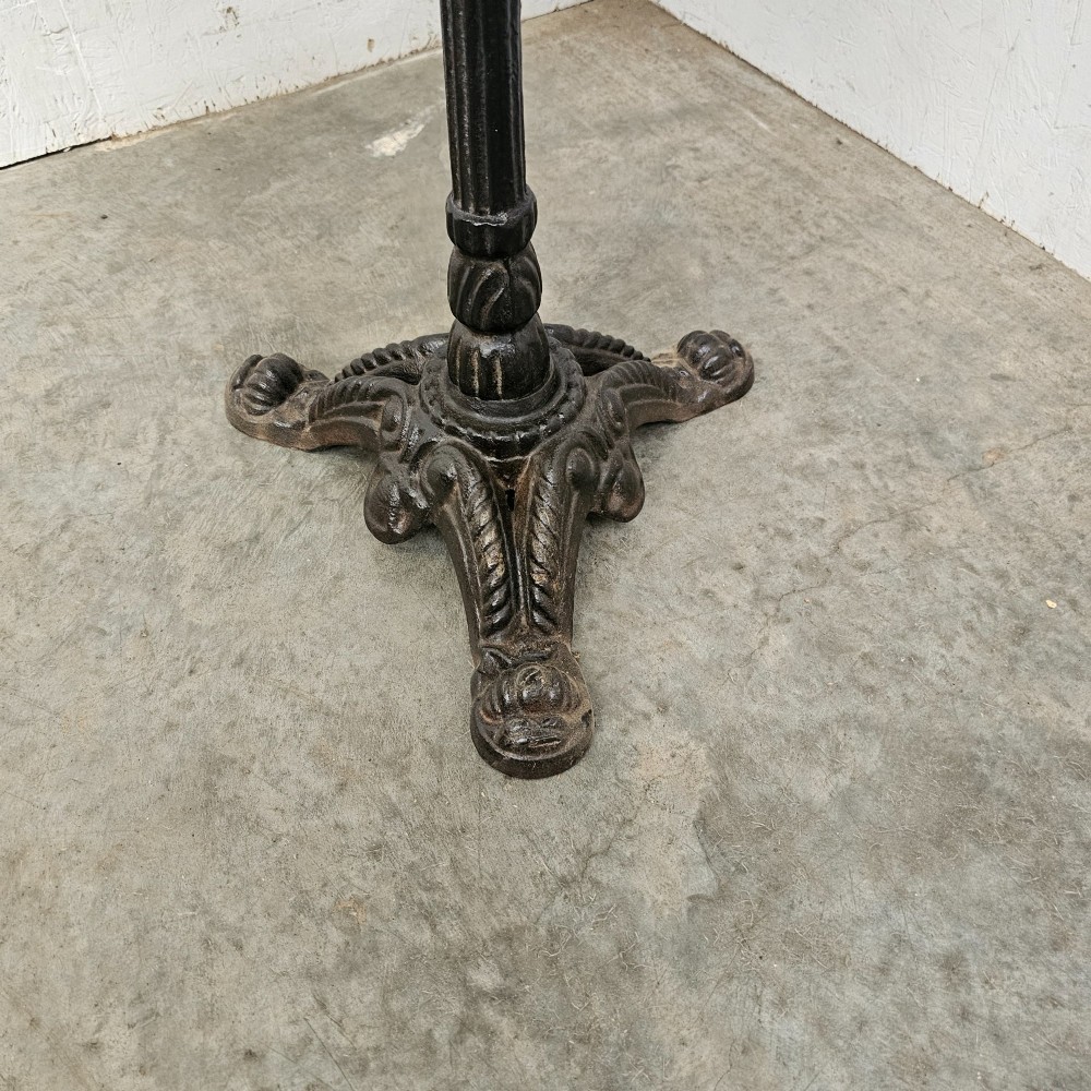 A round white marble top bistro table supported by a black cast iron central column and ornate tripod base. View III