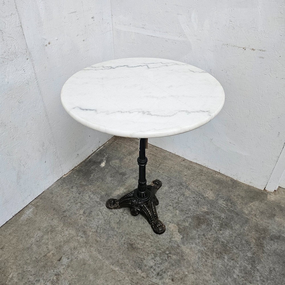 A round white marble top bistro table supported by a black cast iron central column and ornate tripod base. View IV