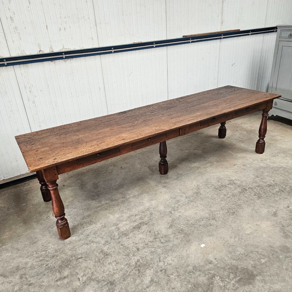 A long rustic chestnut and pine farmhouse dining table featuring six turned legs and multiple side drawers along the wooden frame. View II