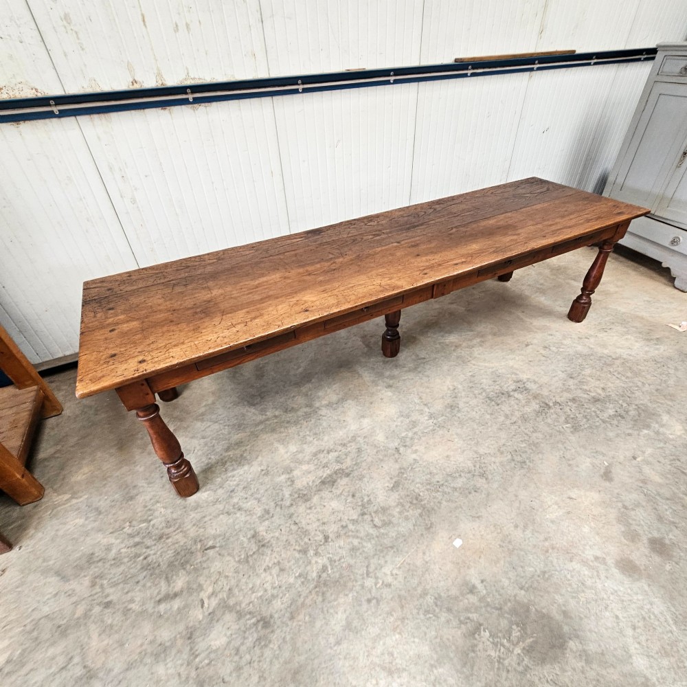 A long rustic chestnut and pine farmhouse dining table featuring six turned legs and multiple side drawers along the wooden frame. View III