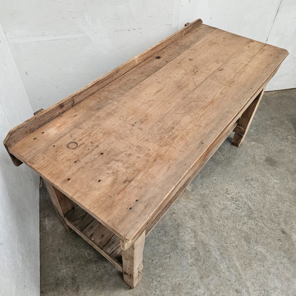 A rustic pine potting table featuring a raised rear upstand, sturdy square legs with a diagonal crossbrace, and a full-length lower timber shelf. View II