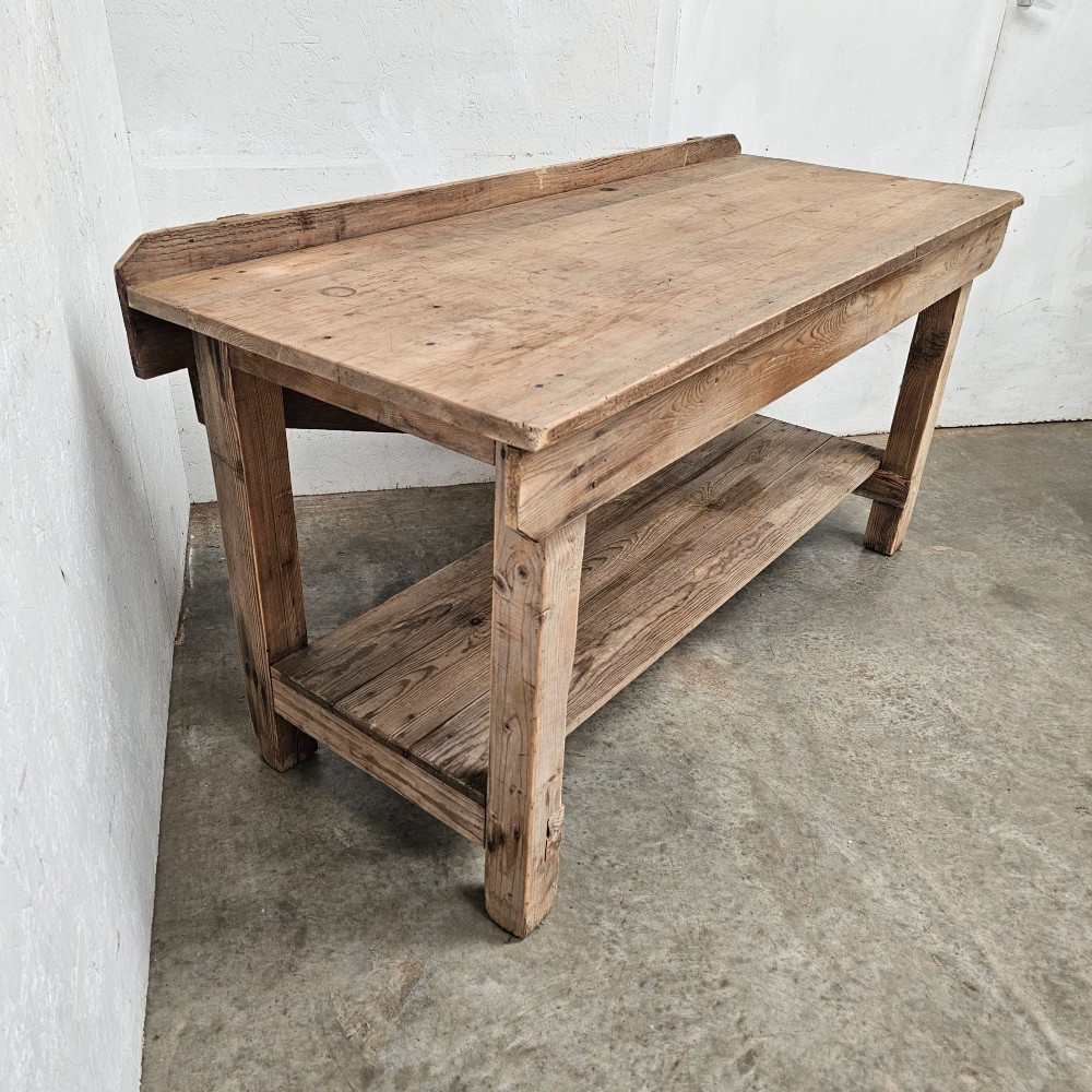 A rustic pine potting table featuring a raised rear upstand, sturdy square legs with a diagonal crossbrace, and a full-length lower timber shelf. View III