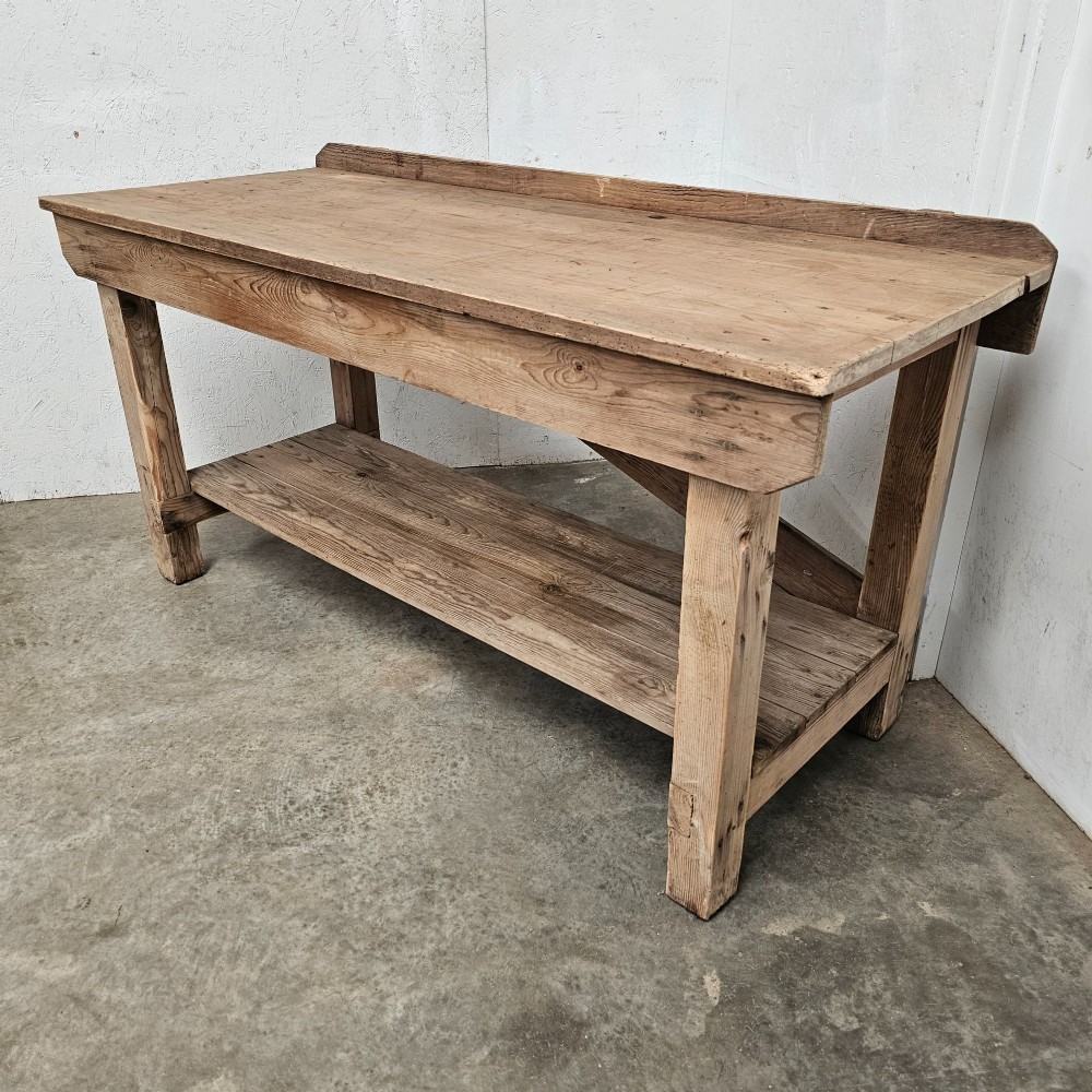 A rustic pine potting table featuring a raised rear upstand, sturdy square legs with a diagonal crossbrace, and a full-length lower timber shelf. View IV