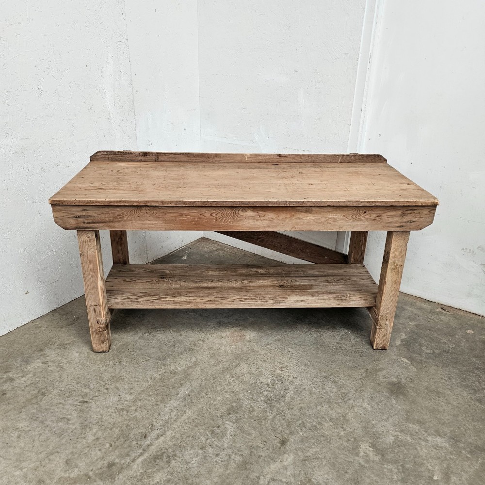 A rustic pine potting table featuring a raised rear upstand, sturdy square legs with a diagonal crossbrace, and a full-length lower timber shelf. View VI