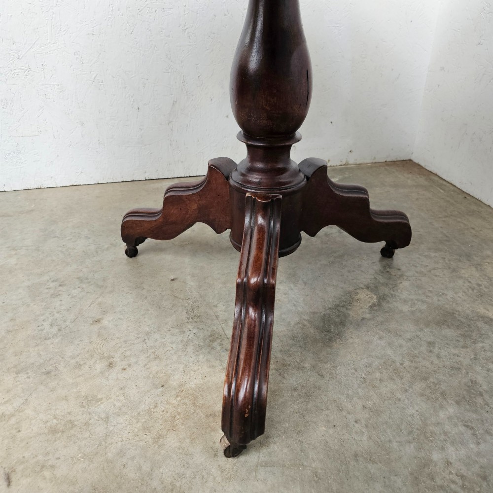 A round antique timber table supported by a central turned pedestal column ending in three carved legs on castors. View III