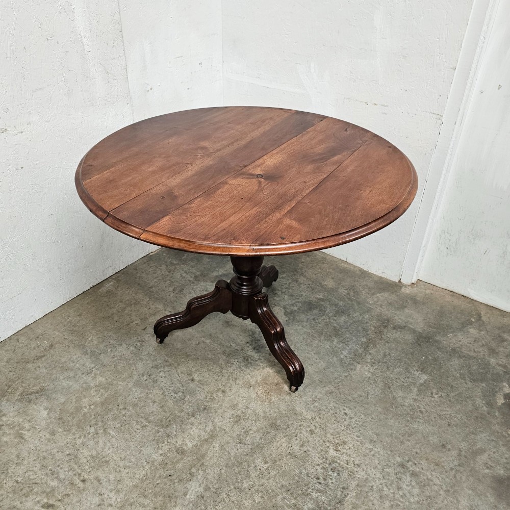 A round antique timber table supported by a central turned pedestal column ending in three carved legs on castors. View IV