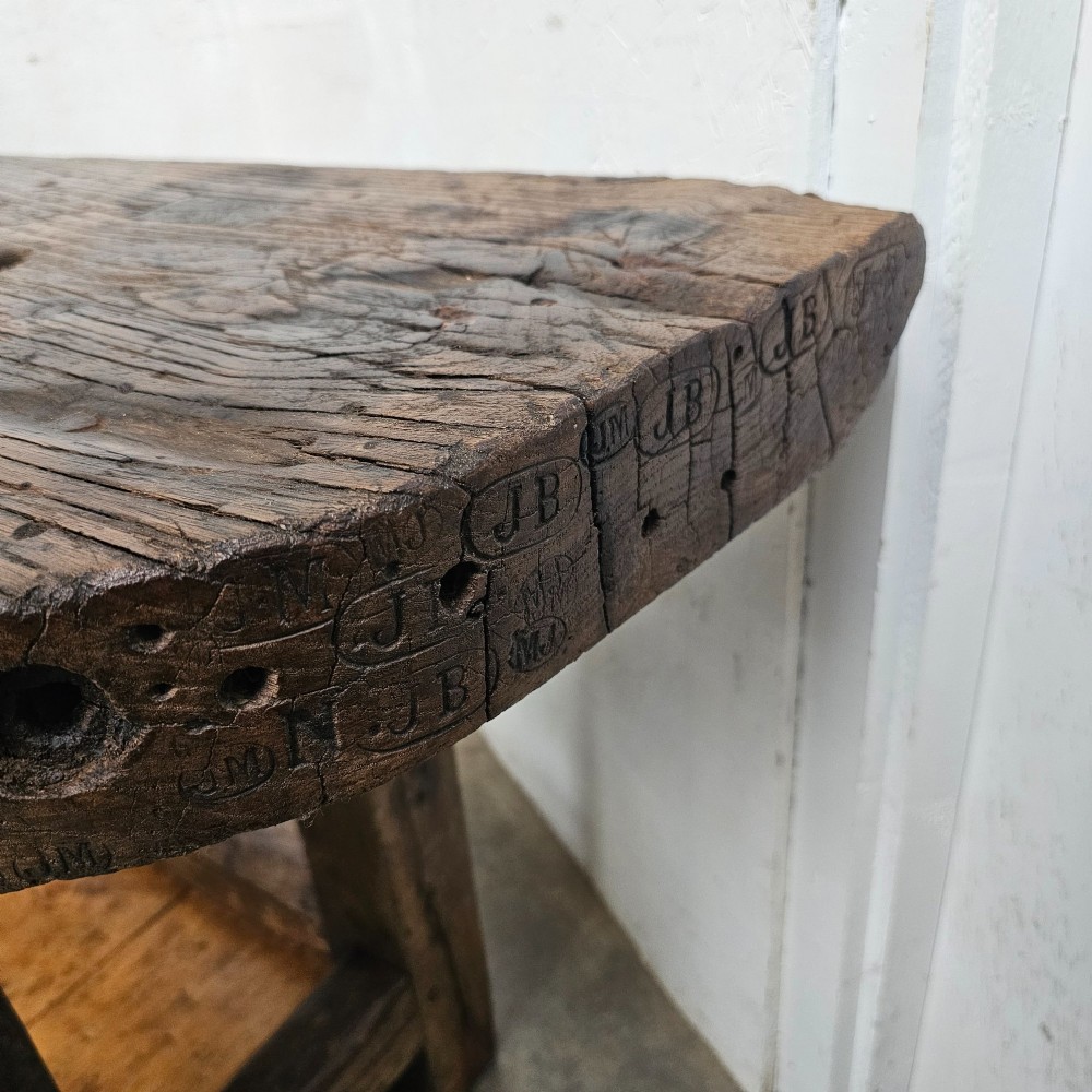 A small primitive French elm workbench featuring a thick distressed wood top, heavy trestle legs, and a lower storage shelf. View II