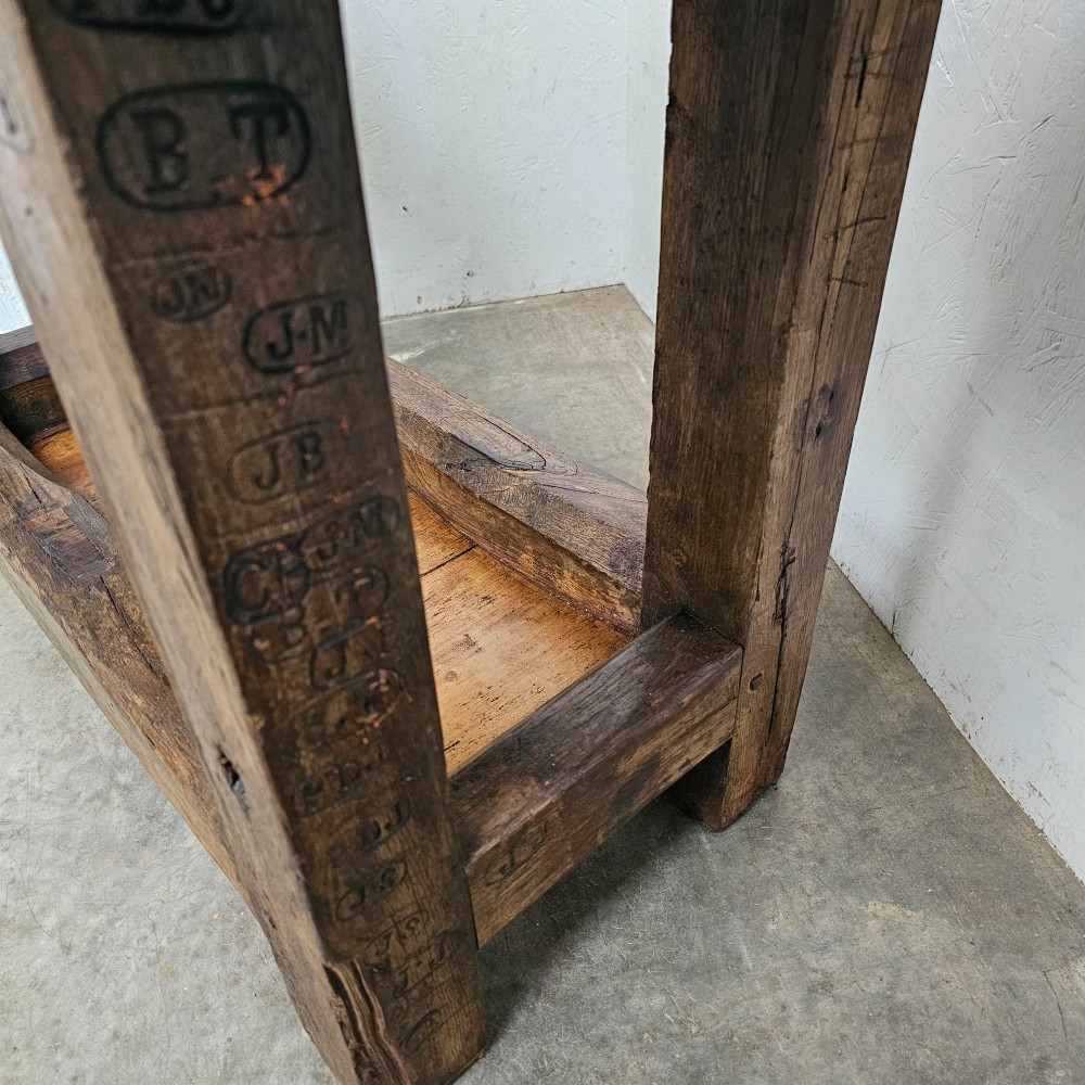 A small primitive French elm workbench featuring a thick distressed wood top, heavy trestle legs, and a lower storage shelf. View III