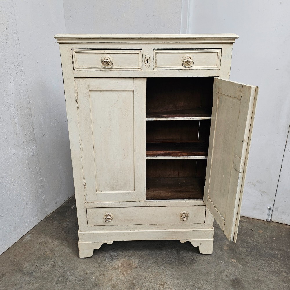 A small off-white painted French linen cupboard featuring two upper drawers, two panelled cupboard doors, and a single lower drawer with drop ring handles. View II